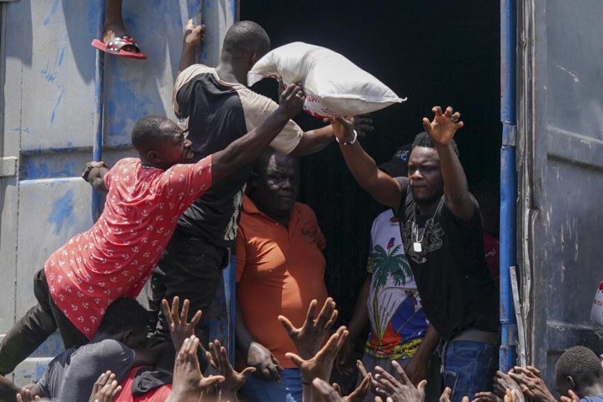  An aid worker tosses a bag of rice last week to survivors of Haiti's August 14 earthquake in Vye Terre, near the hard-hit city of Les Cayes on the country's southwest Tiburon peninsula.