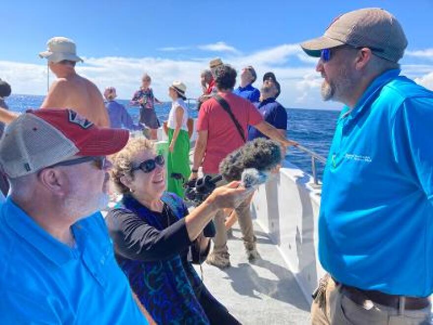 Reporter Sandy Hausman talks with Dominion's Jeremy Slayton (right) and John Larson about the future of offshore wind in Virginia.