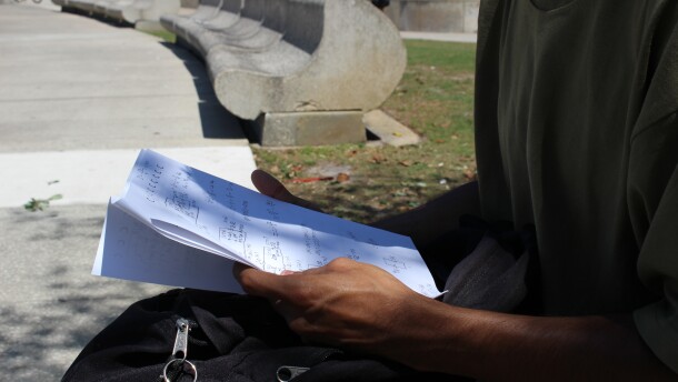 a student holds school work on the UCF campus