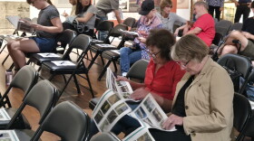 Two women discuss renders as people find their seats at the Matheson History Museum on Sept. 29. The packets include design options for the future site.