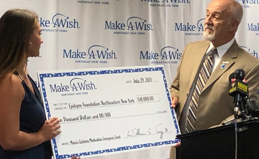 Maria Lutz accepts an oversized check from Make-A-Wish CEO Bill Trigg 