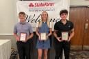 Three student athletes posing and holding plaques