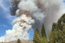 Wildfire smoke fills the sky behind rolling hills.