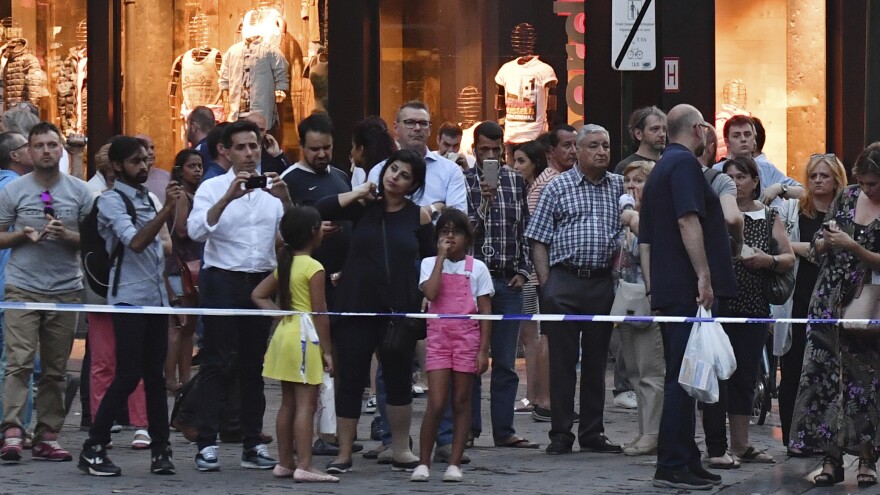 People stand behind police tape as they are evacuated at the Grand Place near Central Station in Brussels after an explosion on Tuesday.