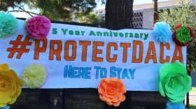 Large white banner reads "5 year anniversary #protectDACA here to stay" with multicolor flowers