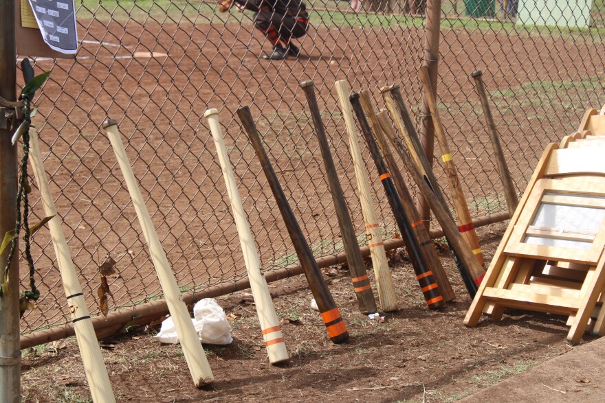 Vintage baseball bats line the fence at a game at Cartwright Field.