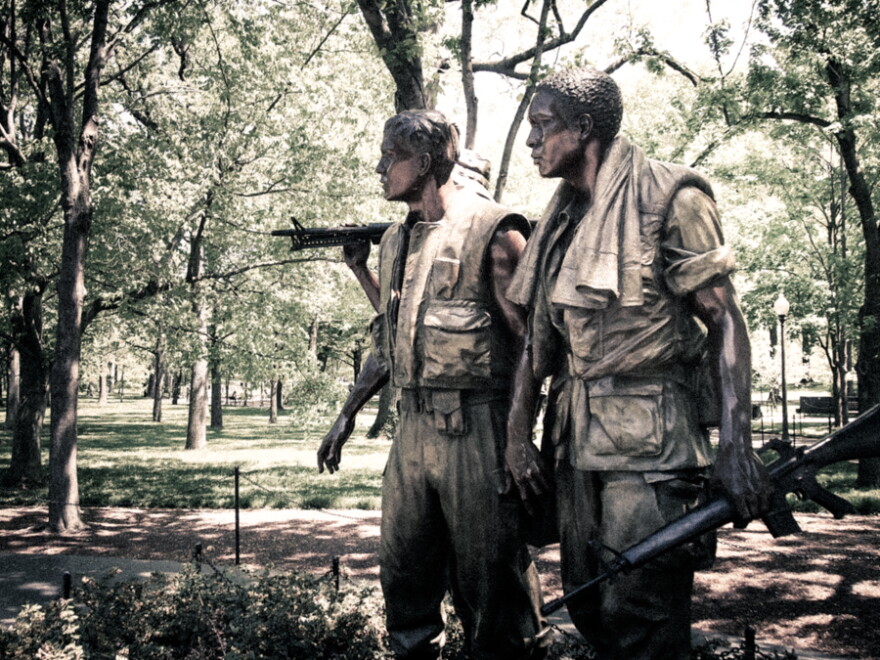 Statue of three soldiers staring in the same direction with one pointing a rifle