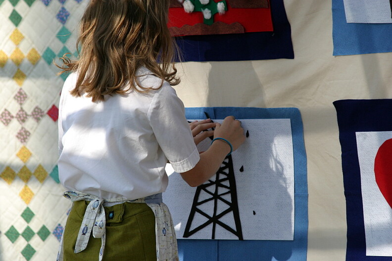 A kid stands in front of art on a wall.