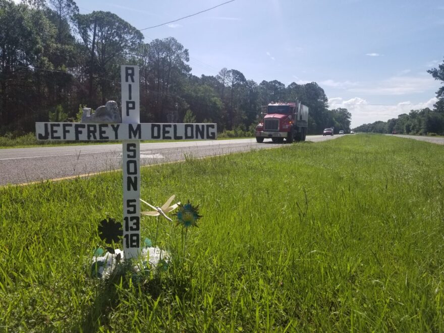 A cross bearing the name of Delong sits at the median of the intersection of County Road 234 and U.S. Highway 441. (Rachael Schirmer/WUFT News)