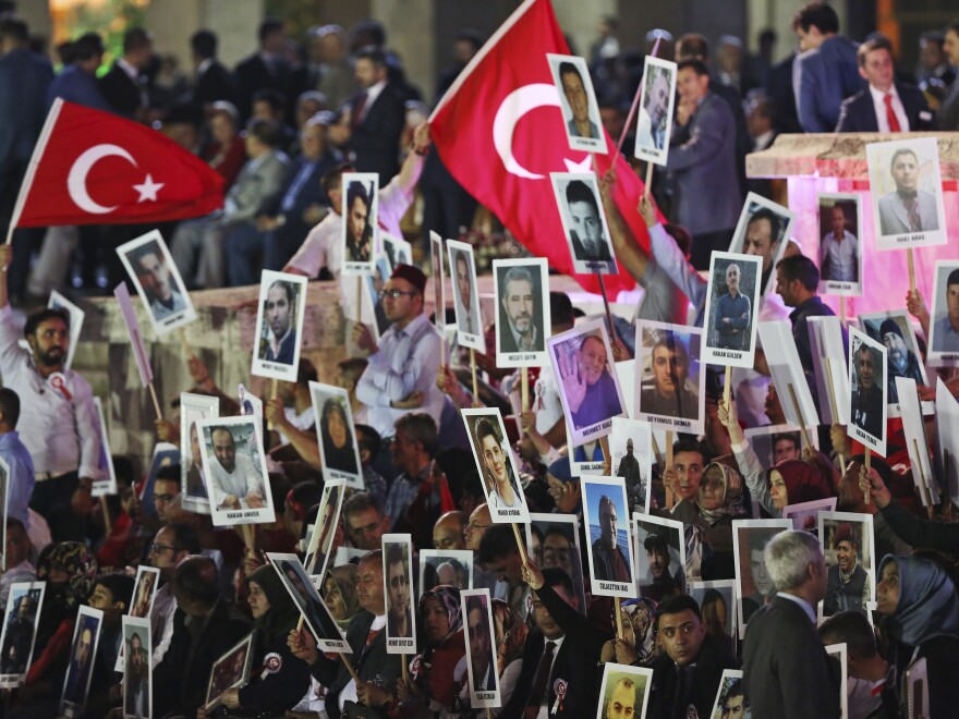 People hold photographs of the victims of the July 15, 2016 failed coup attempt, during a ceremony to commemorate the one year anniversary in Turkey's Parliament in Ankara, Turkey, early Sunday, July 16, 2017.