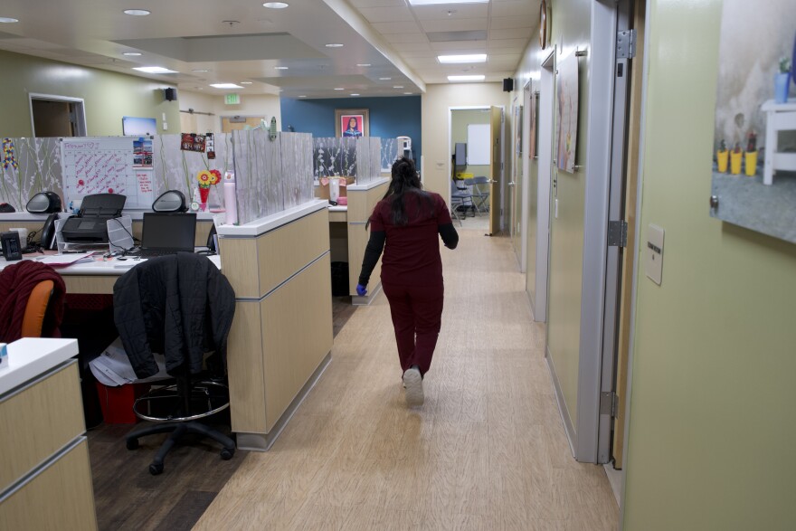 A nurse wearing dark red scrubs walks in a hallway
