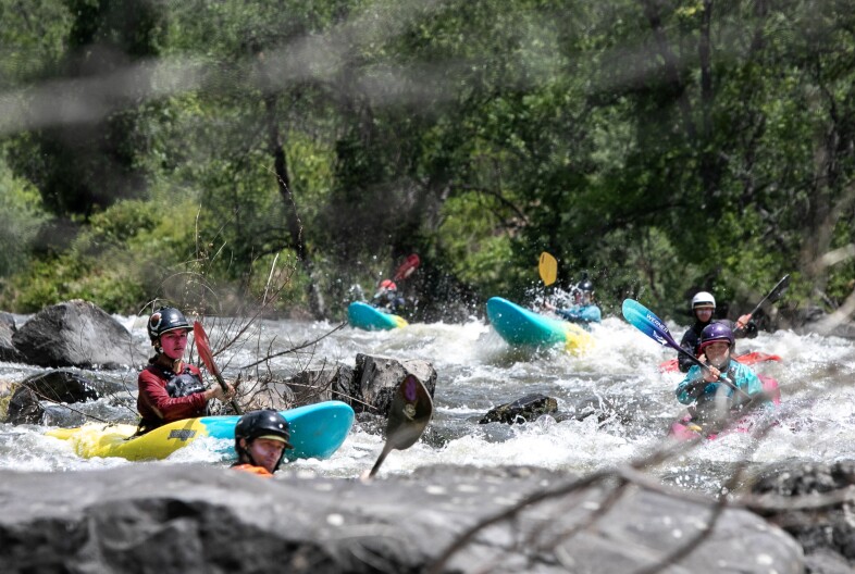 At far left, ‘A:de’ts-Nikya:w Rogers of the Hoopa Valley Tribe pauses at the beginning of a rapid on the Klamath River while other paddlers wait behind him, June 22, 2025. Rogers and the other kayakers are participants in Paddle Tribal Waters, a program that trained Indigenous youth for several years to be the first group of people to paddle the free-flowing Klamath from source to sea.