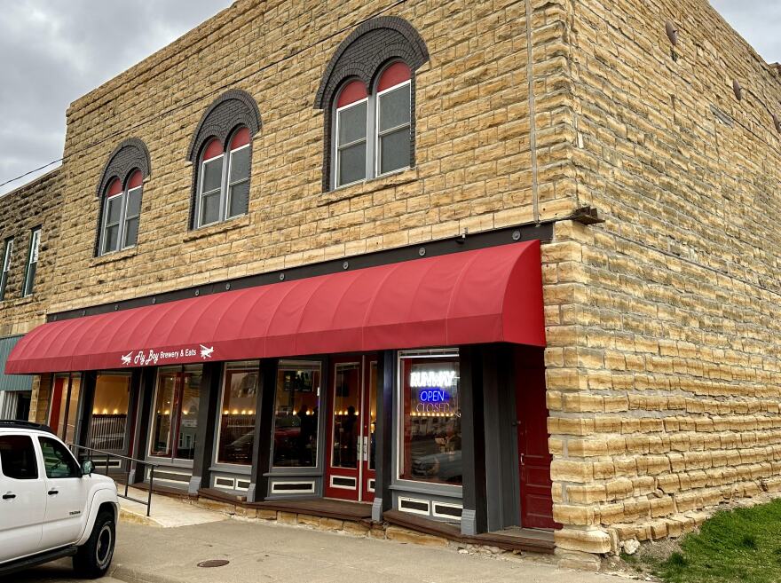 The front of Fly Boy Brewery and Eats, a limestone building with a red awning 