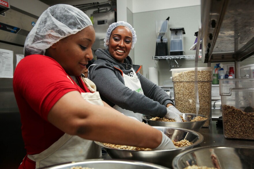 Nikki Yates, a program participant, and Hanna Teklu, a graduate of the program and now a program assistant, mix granola.