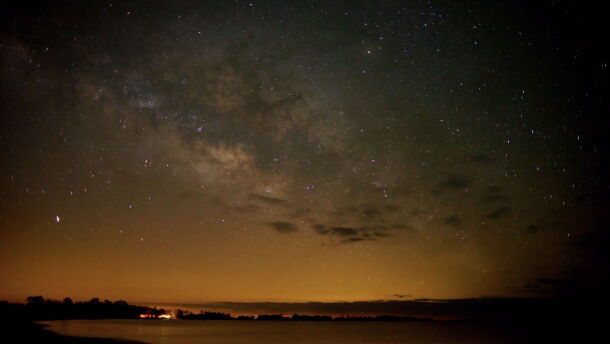 A starry night sky over a body of water.