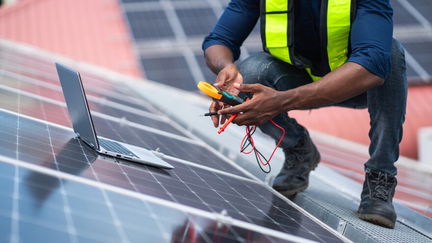 Service engineer checking a rooftop solar panel. Stock photo.
