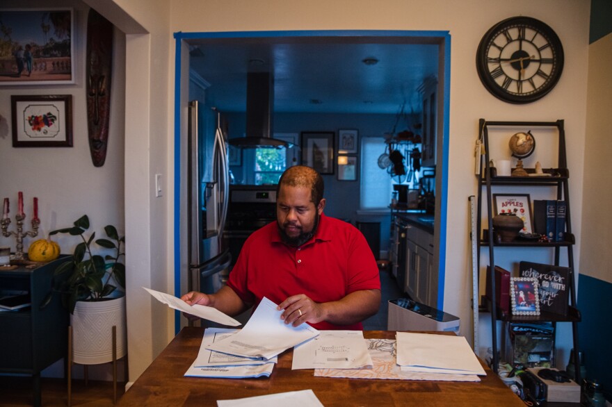 Michael Dew sits in his dining room looking through property records on<strong> </strong>his home in the El Cerrito neighborhood in San Diego, Calif.