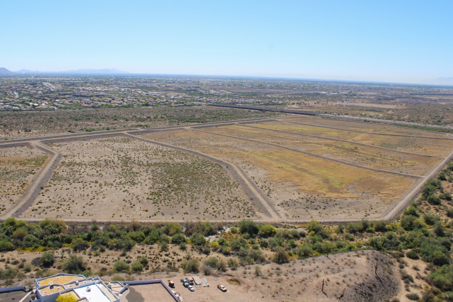 A large desert plain is divided into sections by dirt berms