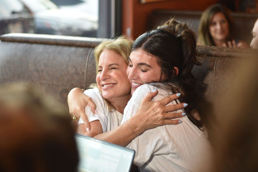 Angie Gallo hugs her daughter as early voting election results rolled in at her watch party.