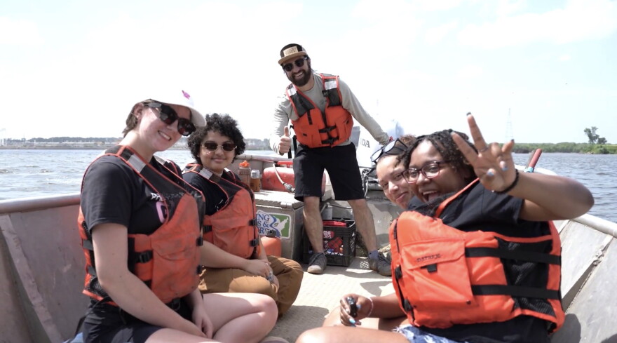 Her Voice Media fellows Abigail Hauser, Satara Masengarb, Kia Sykes, and Tamiah Rogers learn about Mississippi River pollution on the water with Living Lands & Waters vice president Dan Breidenstein, for the documentary, "If the River Were a Woman."