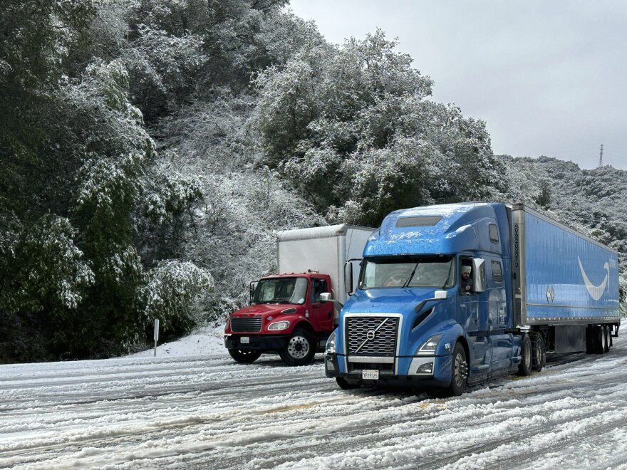 In this photo provided by the Santa Barbara County Fire Department, vehicles drive in the snow near the 2,200 ft summit of San Marcos Pass along Highway 154 in Santa Barbara County, Calif., Thursday, Feb. 23, 2023.