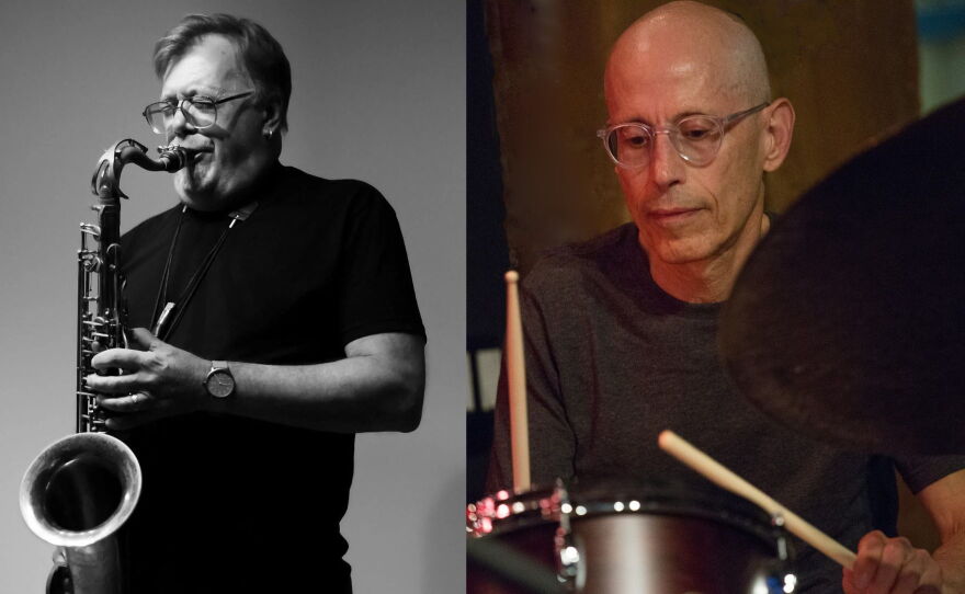 Two guys wearing black t-shirts. The one on the left playing a saxophone and the one on the right playing drums.