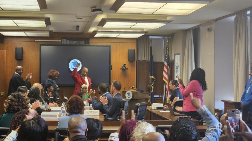New Buffalo Public Schools Board of Education Member Roscoe Henderson III, in red with fist raised, addresses audience members during his swearing-in ceremony