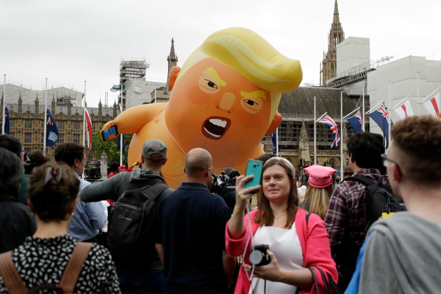 A woman takes a selfie as the "Trump Baby" blimp is inflated in Parliament Square in Central London at the start of the demonstrations.