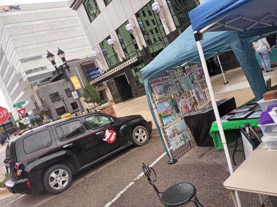 Ryan's car has a custom paint job mashing up the Ghostbusters' Ecto-1 and the Batmobile parked outside of an artist booth in downtown Lansing