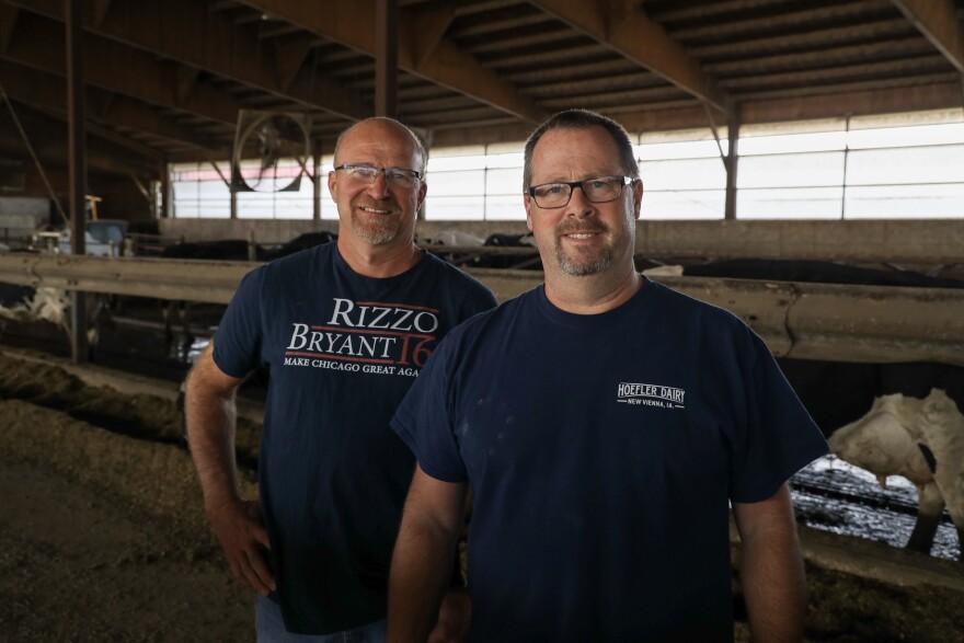 John Hoefler, left, and his husband, Andy Ferguson, stand in the free stall barn at Hoefler Dairy in New Vienna, Iowa, on Oct. 23, 2022.