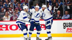 Ondrej Palat on the ice, in the middle, and celebrating a goal with Mikhail Sergachev, left, and Steven Stamkos, right.