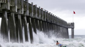 A surfer makes his way out into the water as a subtropical approaches on Monday, May 28, 2018, in Pensacola, Fla. The storm gained the early jump on the 2018 hurricane season as it headed toward anticipated landfall sometime Monday on the northern Gulf Coast, where white sandy beaches emptied of their usual Memorial Day crowds. (AP Photo/Dan Anderson)