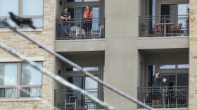 People are seen standing on balconies of their apartments in Austin.