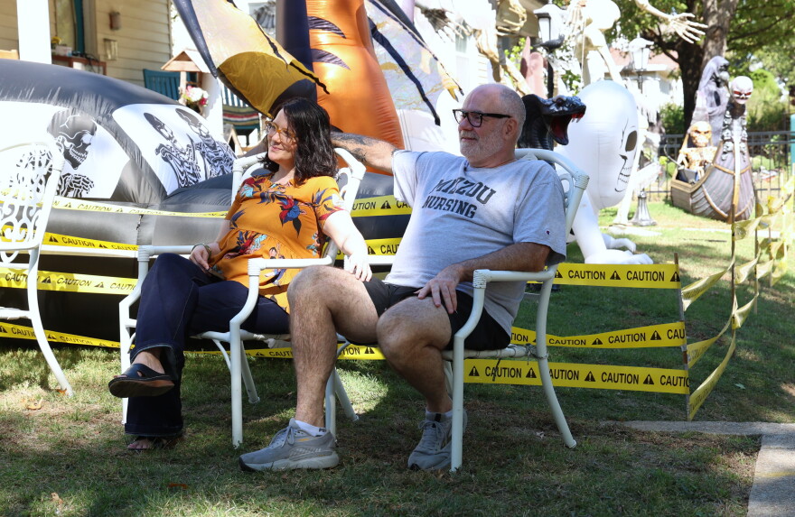 Brittany Lowery and Todd Fullerton watch Trevor C. Smith's performance at the 10th annual North Heights Porchfest. They're sitting in white chairs on the lawn in front of the house.