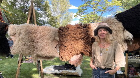A rtist Kelly Moody at the Mountain Harvest Festival standing in front of hides tanned.