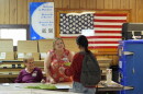 Poll worker hands a voter a ballot at a polling station inside the American Legion in South Miami, Fla.