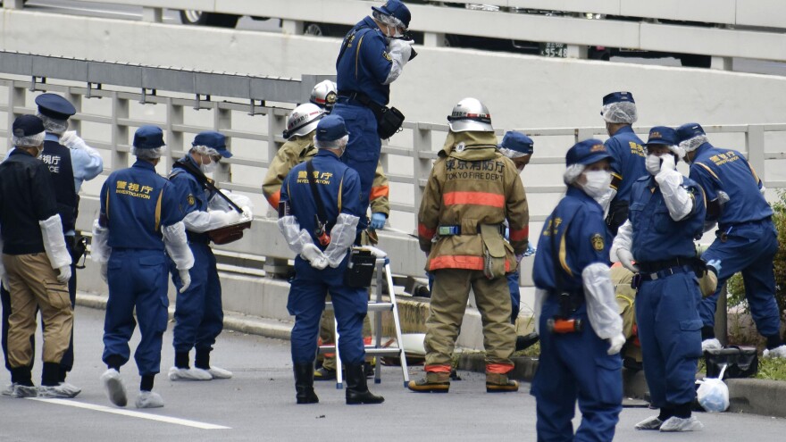 Police and firefighters inspect the scene where a man is reported to set himself on fire, near the Prime Minister's Office in Tokyo on Wednesday.