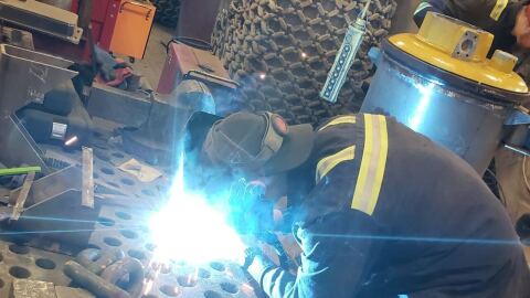 A man in protective gear welds.