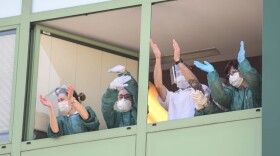 Medical personnel cheers from the windows of a nursing home. (Piero Cruciatti/AFP/Getty Images) 