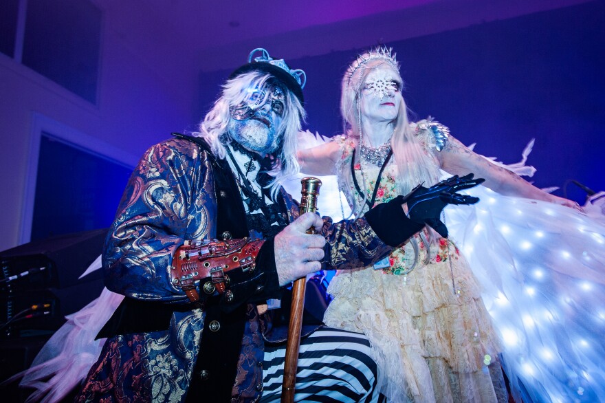 Two costumed figures pose at a ballroom dance. 