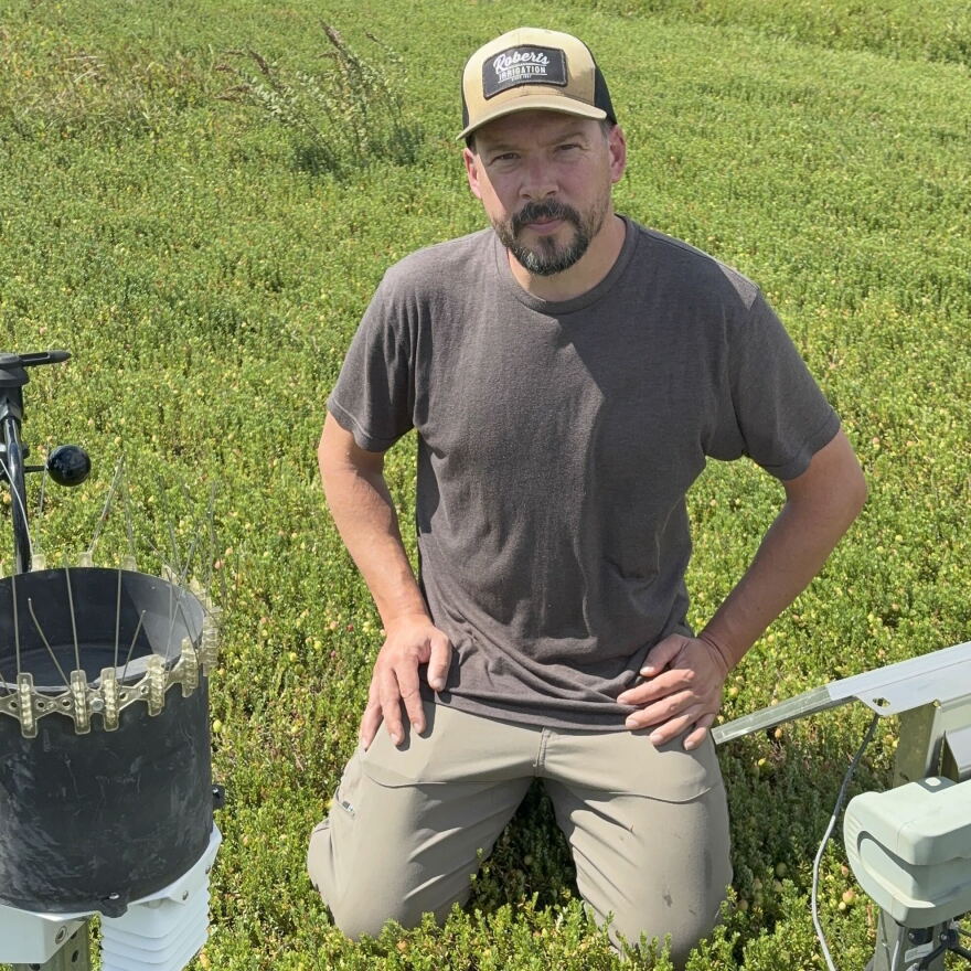 Mike Zawistowski kneels next to the Hortau equipment. It features a wind monitor and a solar power to keep it running.