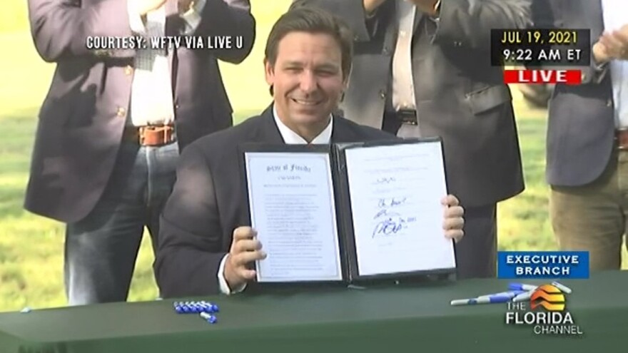 Governor DeSantis holds up the bill