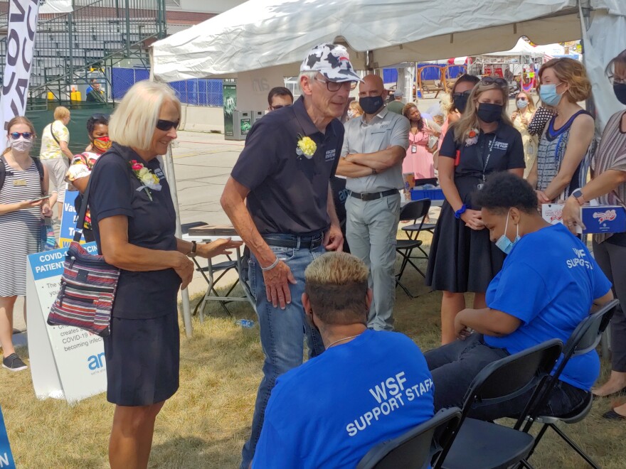 Wisconsin Gov. Tony Evers (in cow hat) speaks with two people who just were vaccinated at the State Fair vaccination booth. Adrianna Winston is at right.