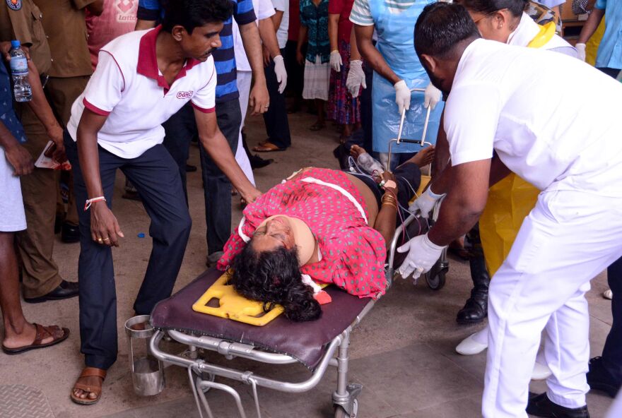 An injured Sri Lankan woman lies on a stretcher as hospital workers transport her at the District General Hospital in Negombo, following the explosion at St. Sebastian's Church.