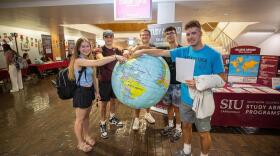 Students pose  with  a large world globe