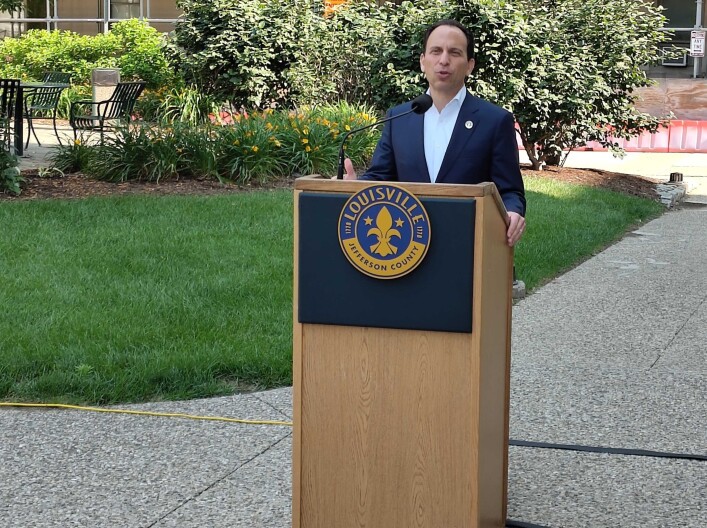 Louisville Mayor Craig Greenberg speaks behind a podium outside.