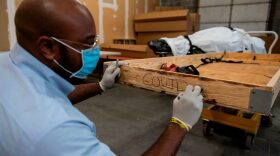 Reggie Elliott, a funeral transporter, writes on the side of a box before depositing the remains of a COVID-19 victim at Maryland Cremation Services in Millersville, Maryland on December 24, 2020 during the COVID-19 pandemic. 
