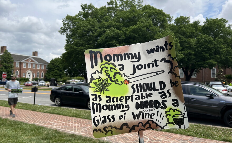 A sign at the rally reads, "'Mommy wants a joint' should be just as acceptable as 'Mommy needs a glass of wine!'"