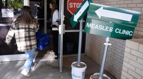 Health department staff members enter the Andrews County Health Department measles clinic carrying doses of the measles, mumps and rubella vaccine, April 8, 2025, in Andrews, Texas.