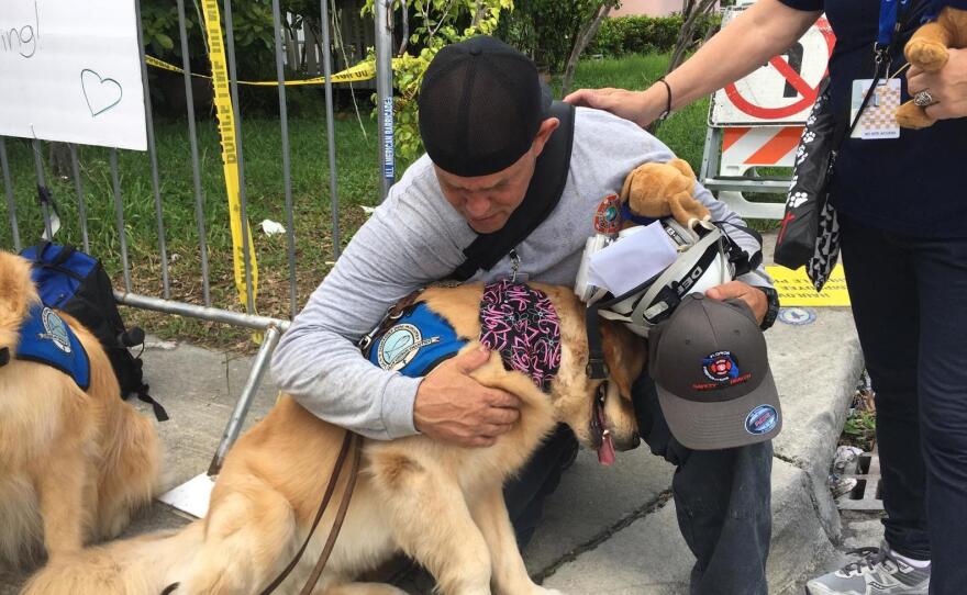 A Florida firefighter at the Surfside collapse hugs Hope, an LCC comfort dog from Georgia.